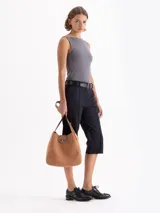 Cartera tipo hobo color marrón oscuro con efecto gastado, confeccionada en cuero vacuno. Tiene un asa de hombro, cierre de torniquete metálico y un sobre interno extraíble.