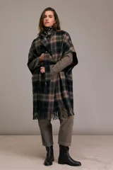 Tapado tipo capa con mangas tres cuartos, confeccionado en mezcla de lana a cuadros en tonos negro, azul, caqui y chocolate. Presenta cuello pequeño con cierre de botón, cierre cruzado con cinturón de tela a juego, mangas anchas hasta el codo, corte holgado y dobladillo con flecos.