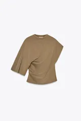 Camiseta color marrón con cuello redondo, manga sisa caída en un lado y manga corta en el otro. Tiene detalle de frunces laterales.