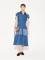 Vestido camisero midi de denim azul con silueta relajada. Tiene mangas cortas rebatidas, recorte a contratono en la falda y acceso frontal con botones.