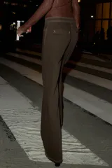 Jeans de tiro alto color marrón oscuro, con pernera recta y detalle de cordones cruzados en la parte delantera central. Presenta costuras contrastantes en color claro.