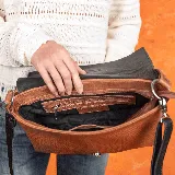 Cartera de cuero vacuno en combinaciones de color negro y whisky, con manija corta y correa larga ajustable.