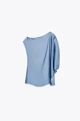 Top celeste de satén con cuello amplio, manga asimétrica y fornitura dorada en el hombro.