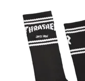 Par de medias blancas con puntera y talón negros. Presentan dos franjas horizontales naranjas en la parte superior y logos de Santa Cruz y Thrasher.