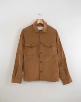 Camisa de pana color marrón, de manga larga, con cuello camisero, cierre frontal de botones y dos bolsillos de parche con solapa en el pecho. Presenta bolsillos laterales ocultos a la altura de la cintura.