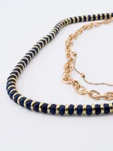 Collar dorado de tres hilos, uno de cuentas azul marino con detalles dorados, uno de eslabones grandes y uno de eslabones pequeños.