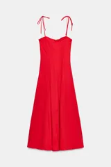Vestido midi rojo de popelín con escote recto, tirantes finos ajustables con lazada y volantes en el escote. Cierre lateral con cremallera oculta.