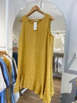 Vestido corto blanco, sin mangas, de corte suelto y con un volante en el ruedo.