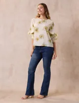 Blusa de gasa color crema con estampado de flores amarillas, de la marca Sioni. Tiene mangas 3/4 con volados y cuello redondo.