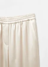 Pantalón largo de satén color crema, con cintura elástica y corte recto.