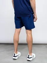 Short deportivo azul con escudo del Club Nacional de Football en la pierna derecha y detalles tricolor.