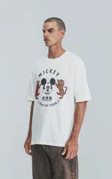 Remera blanca de algodón con cuello redondo y mangas cortas. Estampado frontal con diseño de Mickey Mouse, tigres y texto en inglés y chino.