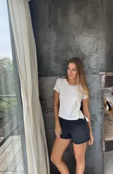 Remera blanca con panel central celeste, cuello redondo y mangas cortas. Presenta detalles de puntilla en el panel lateral.