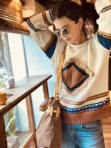 Bolso marrón de cuero gamuza con detalles de correa en cuero mostaza. Tiene una correa corta para llevar como bolso de mano y una correa larga extraíble y regulable. En el interior tiene bolsillo y llavero.