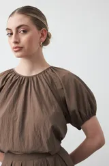 Top negro de manga corta con escote redondo y frunces en la costura de la sisa, creando un efecto de manga abullonada. El tejido parece ligero y con textura.