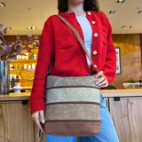 Bandolera marrón con paneles combinados en tonos beige y verde. Tiene apertura superior con cierre, bolsillo frontal con cierre, tres bolsillos internos (dos con cierre), bolsillo trasero con cierre y correa larga regulable.