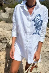 Camisa blanca de lino con bordado de pulpo azul en el pecho, de corte recto y manga larga.