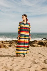 Túnica larga con estampado de rayas horizontales en colores rojo, azul, amarillo, verde y blanco. Tiene cuello camisero, mangas largas y cierre frontal con botones.