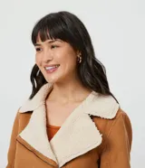 Campera marrón de terciopelo con cuello camisero y forro de sherpa color crema. Tiene cierre frontal con cremallera y bolsillos delanteros con cremallera.