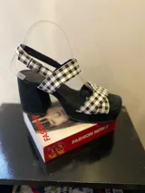 Sandalias de plataforma con taco bloque, capellada con tiras de tela a cuadros blancos y negros, y ajuste con hebilla.