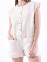 Mono corto color beige con cuello redondo, cierre frontal con botones y bolsillos laterales.