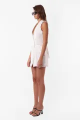 Minivestido blanco tipo blazer sin mangas, con cuello solapa, doble botonadura cruzada, bolsillos ojal y tira de ajuste en la espalda.