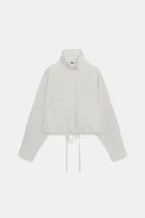 Chaqueta corta de nylon con cuello alto, manga larga y bajo ajustable con cordones. Presenta un estampado de cuadros pequeños en tonos claros.