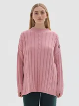 Buzo tejido de algodón color rosado, con cuello subido tipo polera, corte oversized, largo y con pequeños cortes laterales.