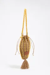 Bolso de mano tejido a crochet en color marrón con rayas horizontales amarillas, asa corta tejida a crochet color amarillo, cierre ajustable con cordones y borla colgante.