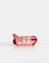 Broche para el pelo de acrílico color rosa con diseño de flores blancas.