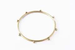 Pulsera rígida dorada con pequeñas esferas decorativas.