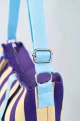 Bolso tipo tote bag con diseño a rayas verticales blancas y negras, doble asa de mano rosa y correa de hombro ajustable y removible también rosa.