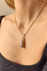 Collar dorado con cadena fina y dije colgante en forma de lágrima de piedra natural azul con vetas blancas.