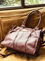Bolso tipo tote de cuero color borgoña con doble asa de hombro, correa bandolera ajustable y detalles de costuras a la vista.