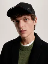 Gorra negra de estilo informal con logo de Tommy Hilfiger en la parte frontal y cinta distintiva en la parte trasera.