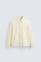 Sobrecamisa color crudo de corte regular fit, confeccionada en tejido con mezcla de viscosa. Tiene cuello solapa, manga larga con puños abotonados, bolsillo de parche en el pecho, bajo ajustable con cordones y cierre frontal con botones.