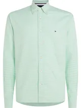 Camisa Tommy Hilfiger de hombre, modelo 1985, de corte regular, confeccionada en algodón orgánico Oxford con diseño de cuadros Vichy en tonos verde y blanco. Presenta cuello abotonado, puños redondeados con doble botón y logo bordado en el pecho.