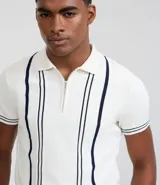 Camisa polo de punto color crema con rayas verticales azul marino, cierre de cremallera, cuello polo y mangas cortas con ribete a juego. Corte slim fit.