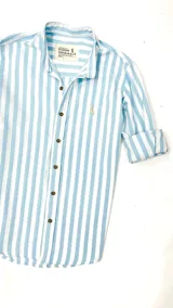 Camisa de manga larga a rayas verticales celestes y blancas, con cuello mao, cierre frontal con botones marrones y logo bordado en el pecho.