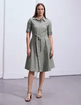 Vestido camisero blanco de algodón con cuello con solapa, delantera abotonada, mangas 3/4 regulables con presilla y botón, y cintura con lazo de ajuste.