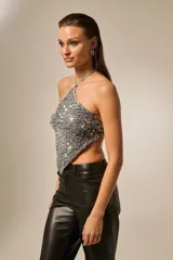 Top sin mangas de poliéster, color plateado, con lentejuelas, cuello halter y diseño anudado al cuerpo.