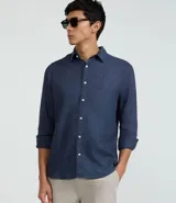 Camisa de lino azul marino de corte clásico, con cuello inglés, manga larga y abotonadura frontal.