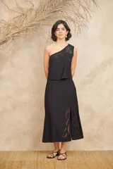 Conjunto negro de dos piezas de lino, compuesto por un top de un hombro con bordados florales y una falda midi con aberturas laterales y bordados florales.