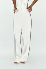 Pantalón blanco de tela satinada, tiro alto, corte ancho y pliegues en la parte delantera y trasera.