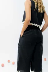 Top de lino color crudo, con escote cuadrado y detalle de guarda ondulada negra en el ruedo.