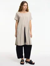 Vestido largo color beige de tejido de punto, con mangas cortas y tajo frontal.