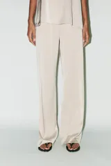 Pantalón de vestir color crema de tela satinada, corte palazzo y tiro alto.