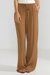 Pantalón de crepe color marrón, de corte recto con cintura elastizada y bolsillos laterales.