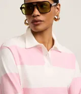 Remera de manga larga con cuello polo, a rayas horizontales anchas de color rosado y blanco.