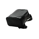 Mochila negra con monograma de la marca MCM estampado en toda la superficie. Confeccionada en lona revestida en cuero, con cierre bidireccional, asa superior reforzada, correas ajustables, dos compartimientos interiores (uno para tablet), bolsillo interior y exterior con cierre, y placa metálica con el logo en la parte posterior.